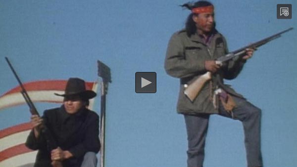 screenshot of video shows two Native American men holding rifles