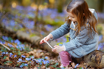 – young girl outdoors taking photos of nature with a mobile device